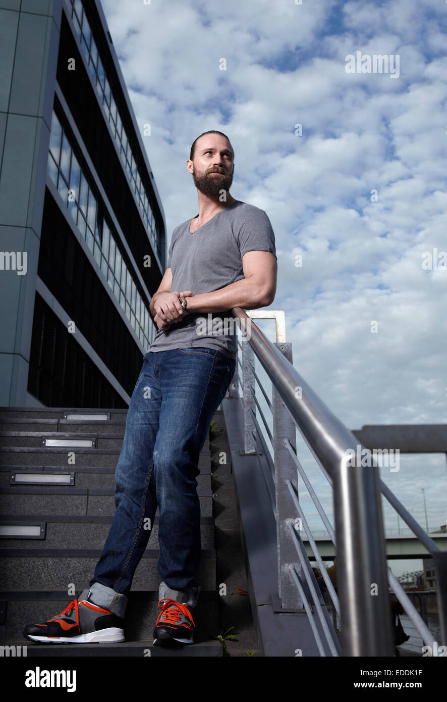 Portrait of man with full beard leaning on railing Stock Photo