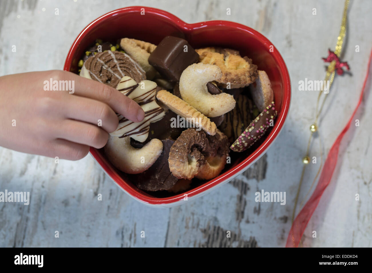 Children's hand taking Christmas cookie from a heart-shaped bowl Stock Photo