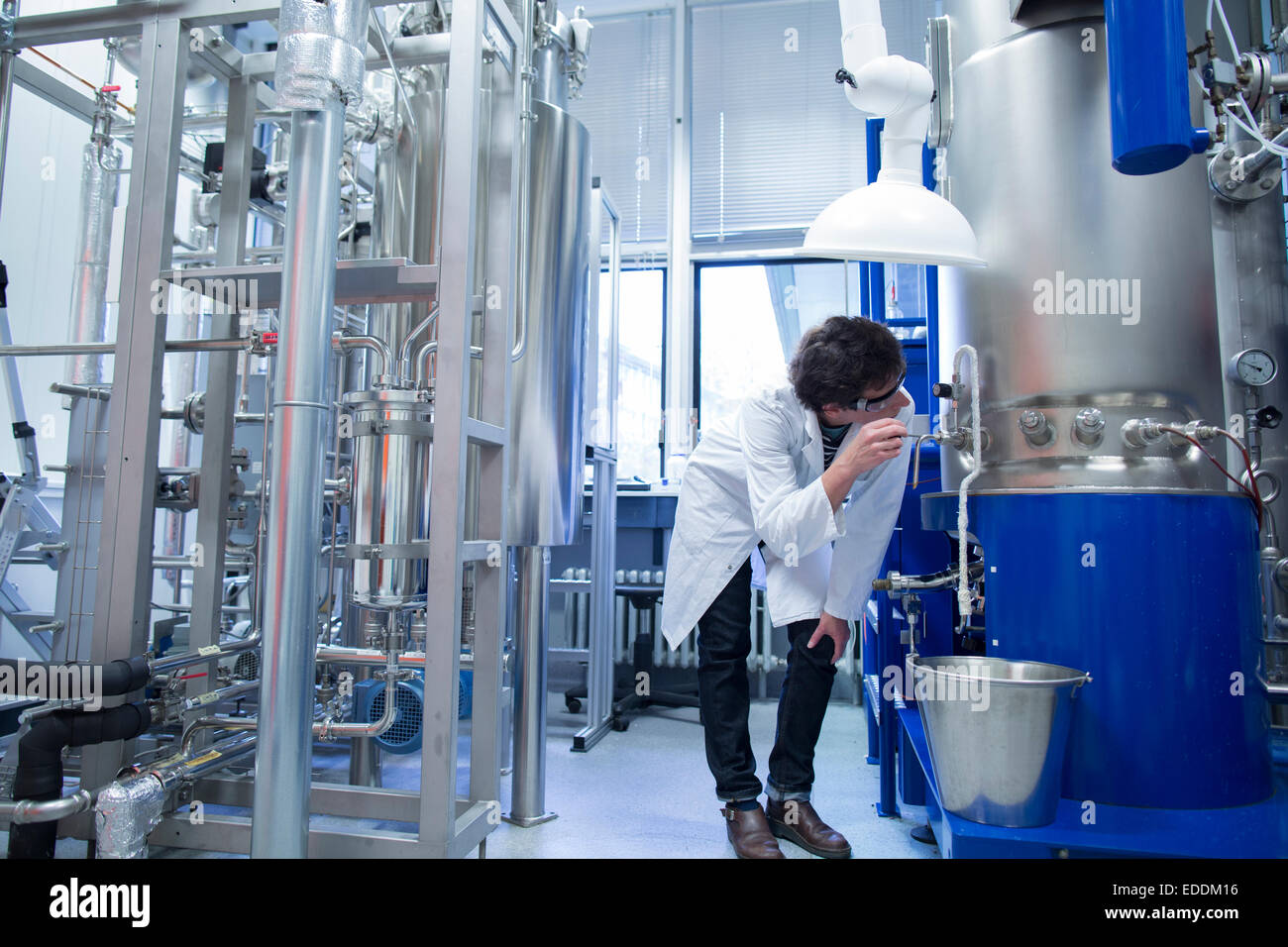 Woman with lab coat in technical room with a fermenter Stock Photo