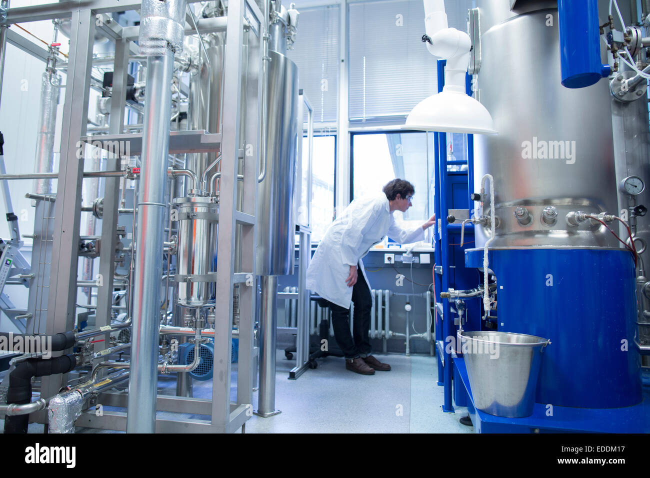 Woman with lab coat in technical room with a fermenter Stock Photo