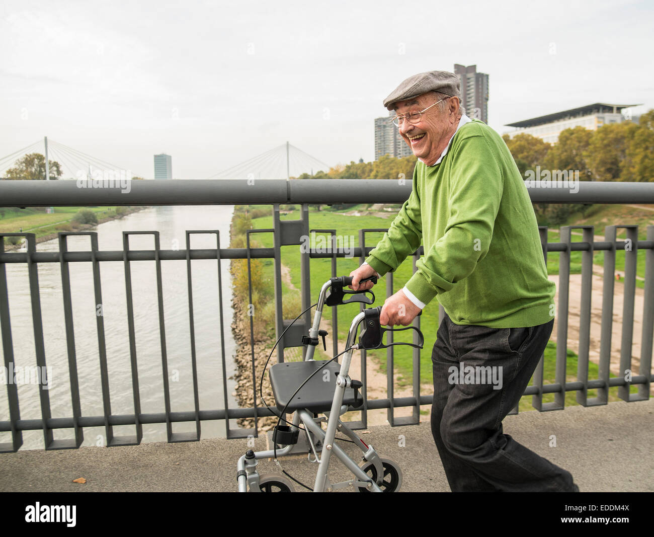 Playful senior man with wheeled walker on bridge Stock Photo