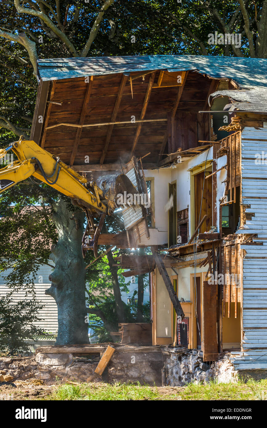 The arm of a mechanical digger moves to demolish the remnants of a house in Falmouth, Massachusetts - USA Stock Photo