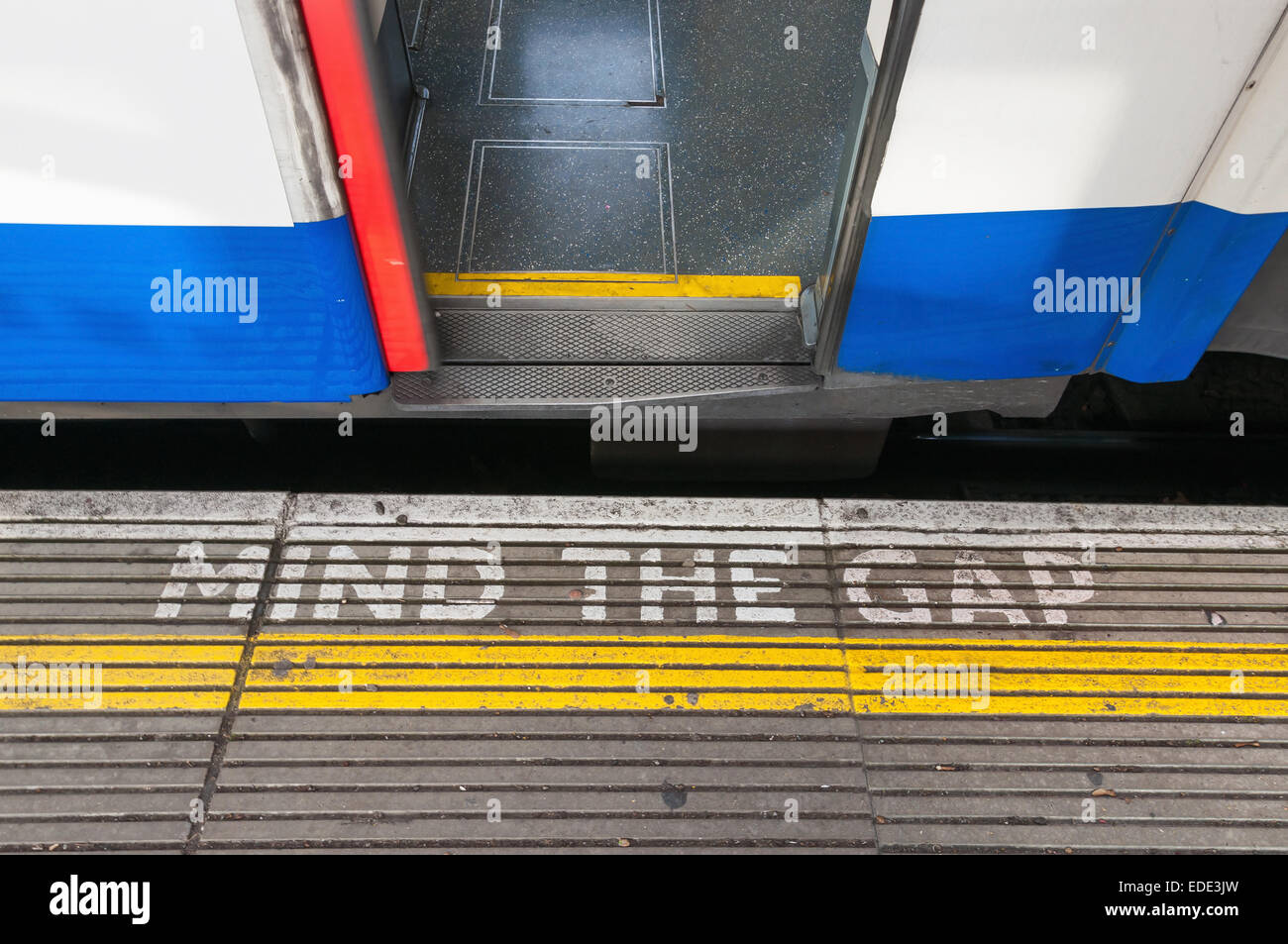 Closeup of mind the gap sign on a platform edge with open train door Stock Photo