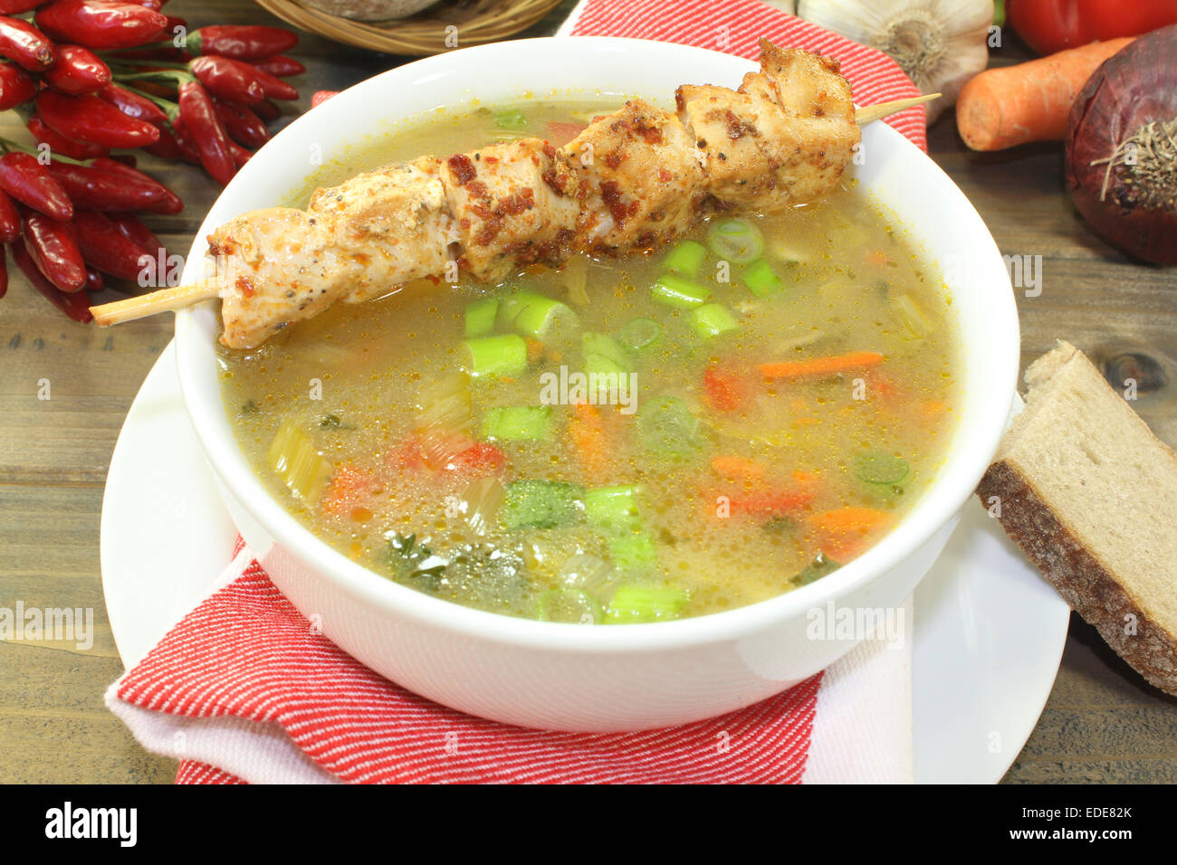 a chicken consomme with a chicken skewer Stock Photo Alamy