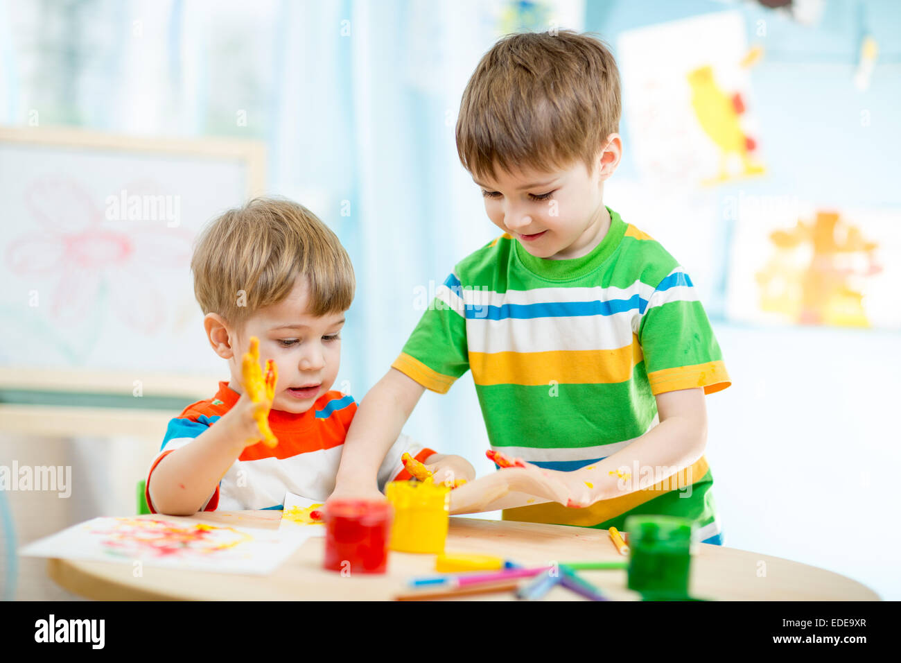 smiling kids play and paint at home or kindergarten or playschool or daycare Stock Photo