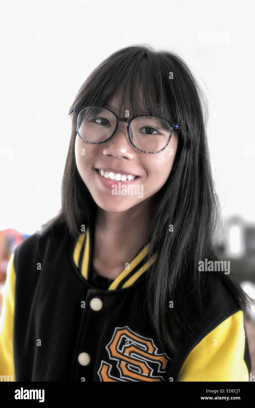 Girl wearing glasses and an American college baseball jacket. Asian teen girl Stock Photo