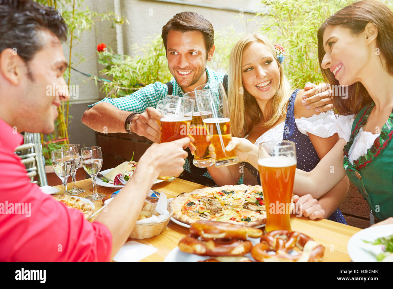 Happy friends in bavaria celebrating with beer and pizza in summer Stock Photo