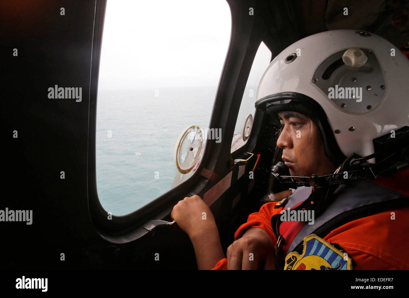 Pangkalan Bun, Indonesia. 6th Jan, 2015. A crew member of an Indonesian Air Force NAS 332 Super Puma helicopter looks out of the window during a search operation for the victims of AirAsia QZ 8501 over the Java Sea off Pangkalan Bun, Indonesia, Jan. 6, 2015. The search operation for AirAsia Flight QZ8501 will spread slightly eastward on Tuesday as the weather and currents drag wreckage in that direction, the head of Indonesia's rescue agency said. Credit:  Pool/Achmad Ibrahim/Xinhua/Alamy Live News Stock Photo