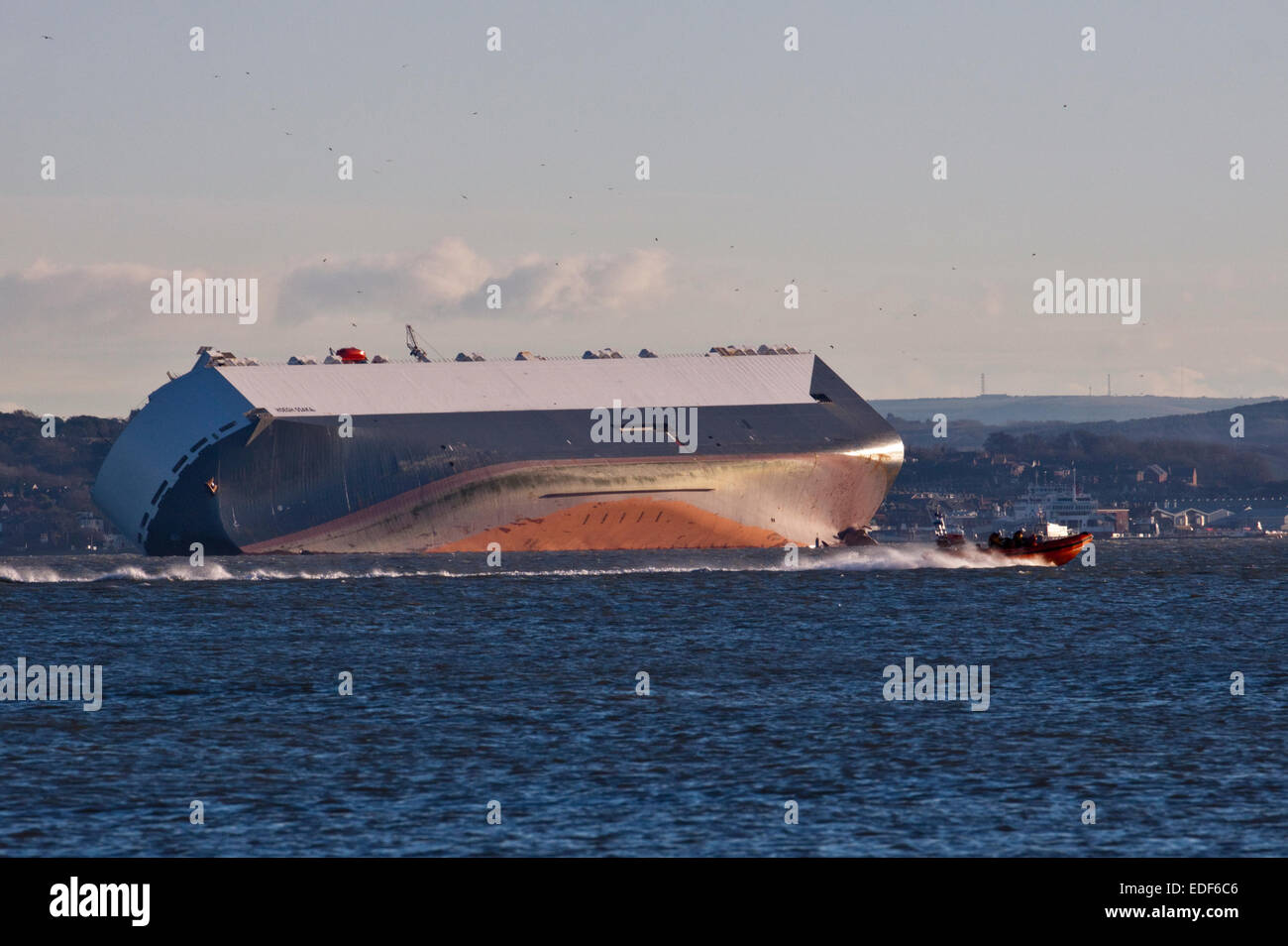 Solent, Hampshire, UK. 6th January, 2015. Hoegh Osaka Car Transporter Ship run aground in the Solent, Hampshire, England - awaiting salvage plans - possible salvage crew crossing in front of ship. 06Jan15 Credit:  Krys Bailey/Alamy Live News Stock Photo