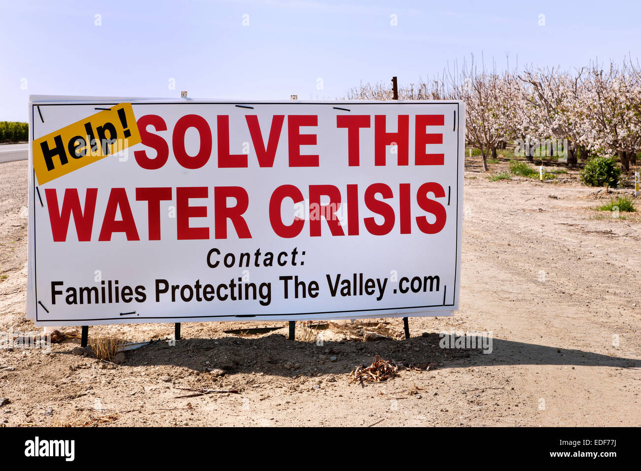 Sign, 'Help!  Solve  The Water Crises'  posted by flowering almond  orchard, Stock Photo