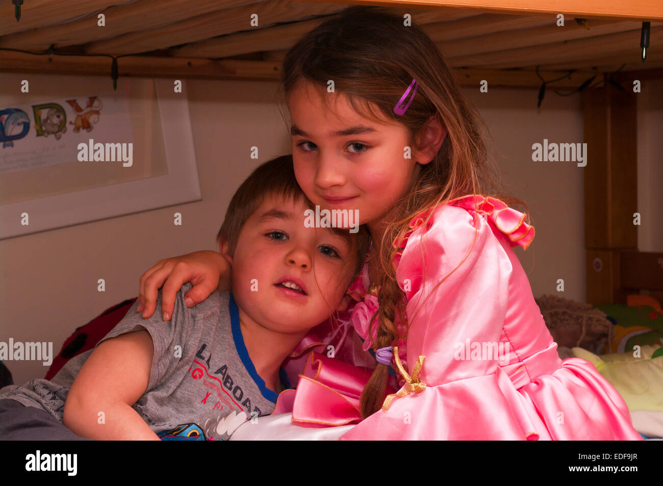 Young Brother and Sister Cuddling Looking At The Camera Stock Photo