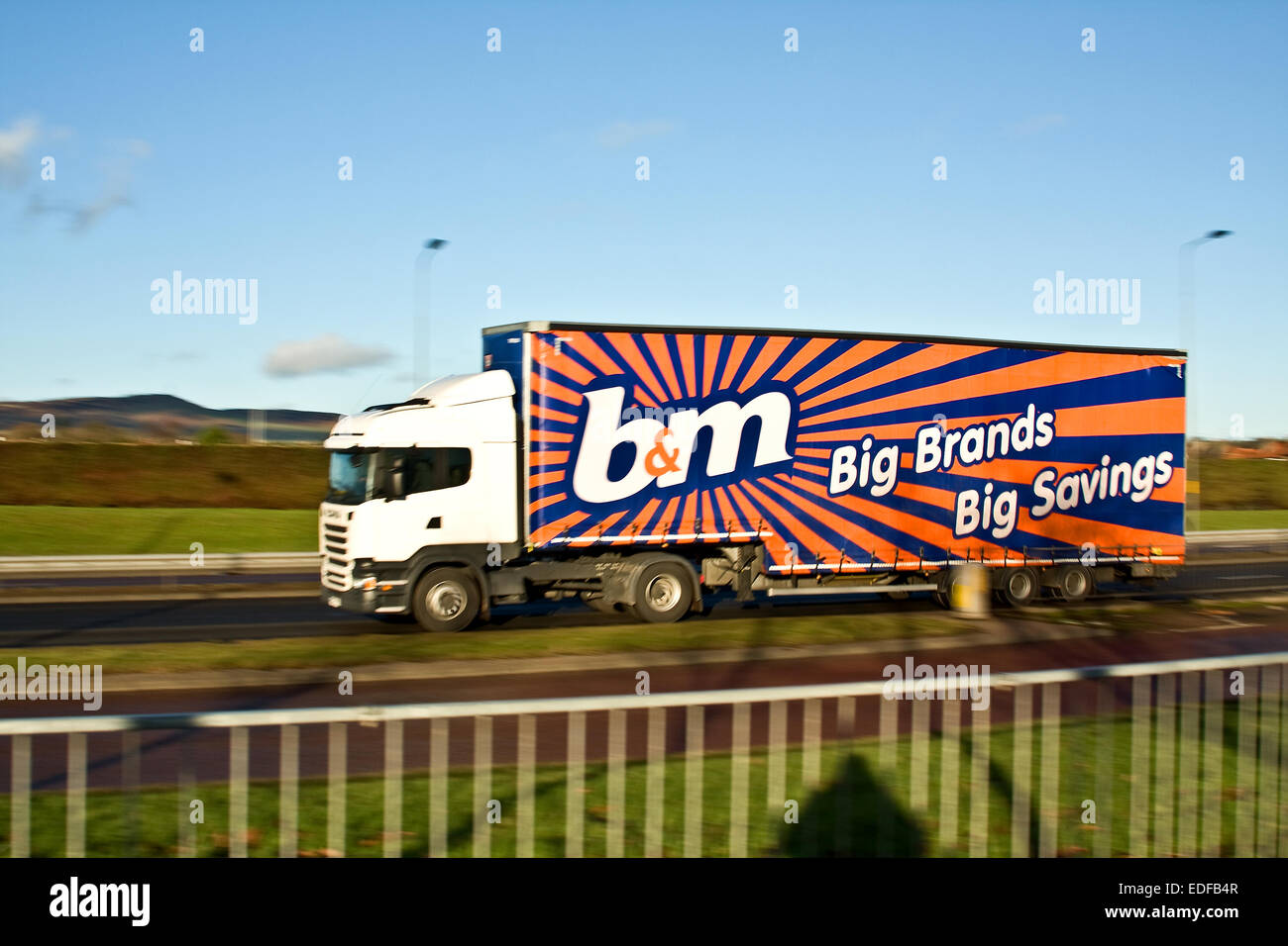 Panning a B&M Bargains articulated lorry with rear sync flash travelling along the Kingsway West Dual Carriageway in Dundee, UK Stock Photo