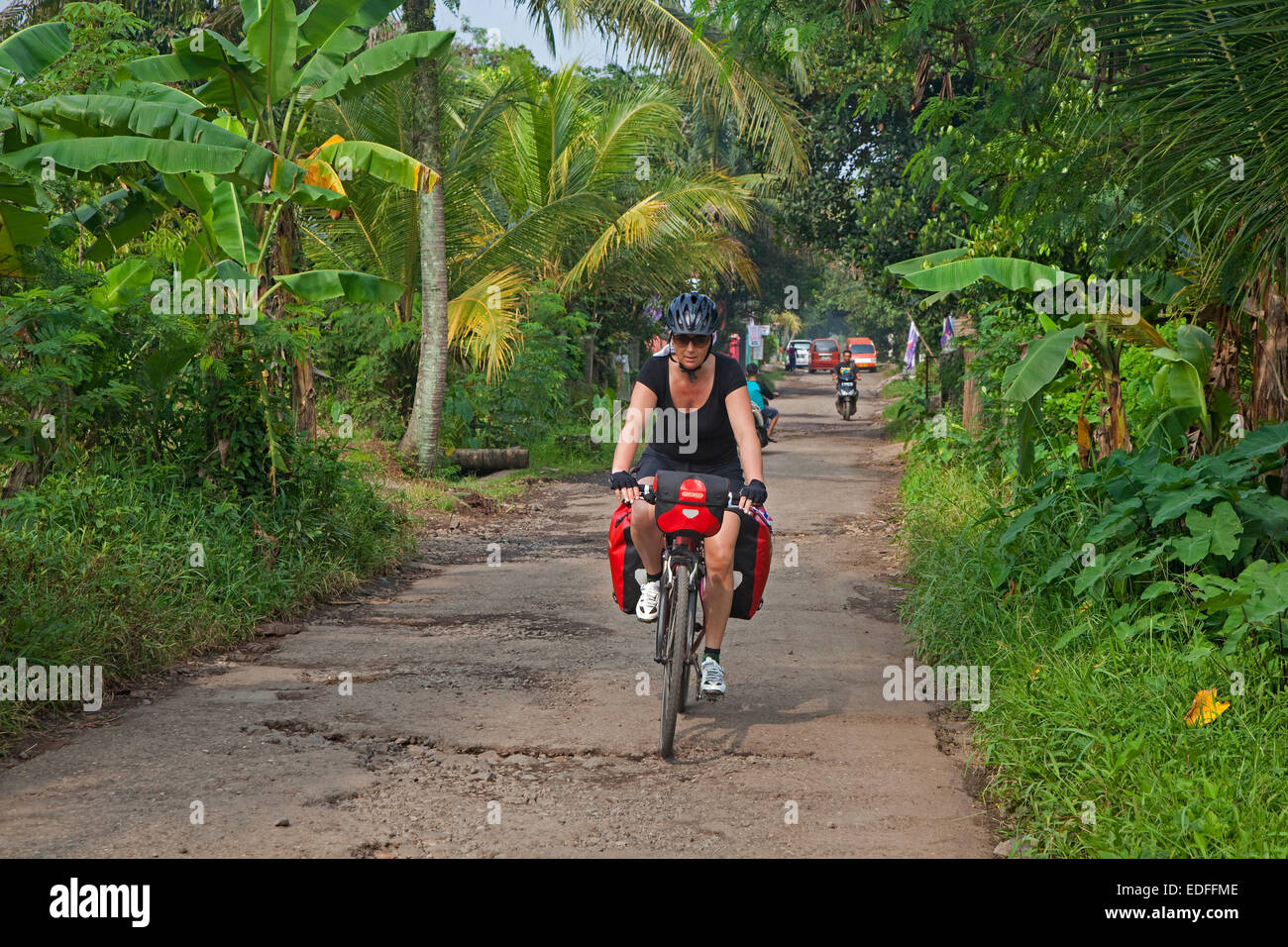 Western tourist cycling along rural country road in the Cianjur Regency, West Java, Indonesia Stock Photo