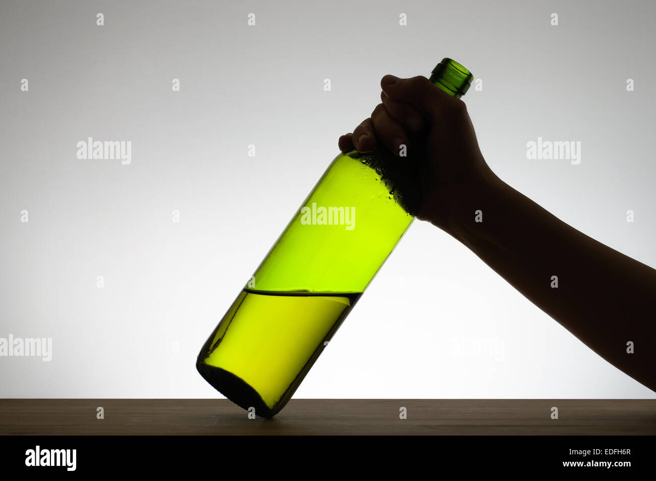Silhouette of a hand grabbing a green wine bottle Stock Photo
