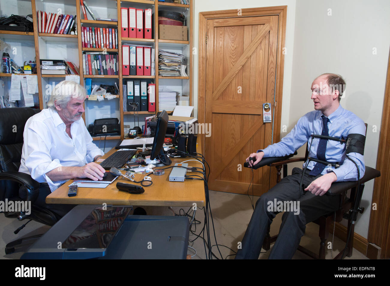 Man being examined using a Polygraph test lie detector machine which compares responses to selected questions to gain the truth Stock Photo