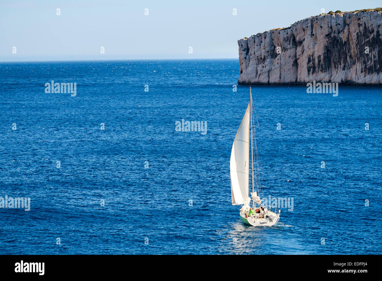 Aft (rear) view of small sailboat heading out to sea Stock Photo