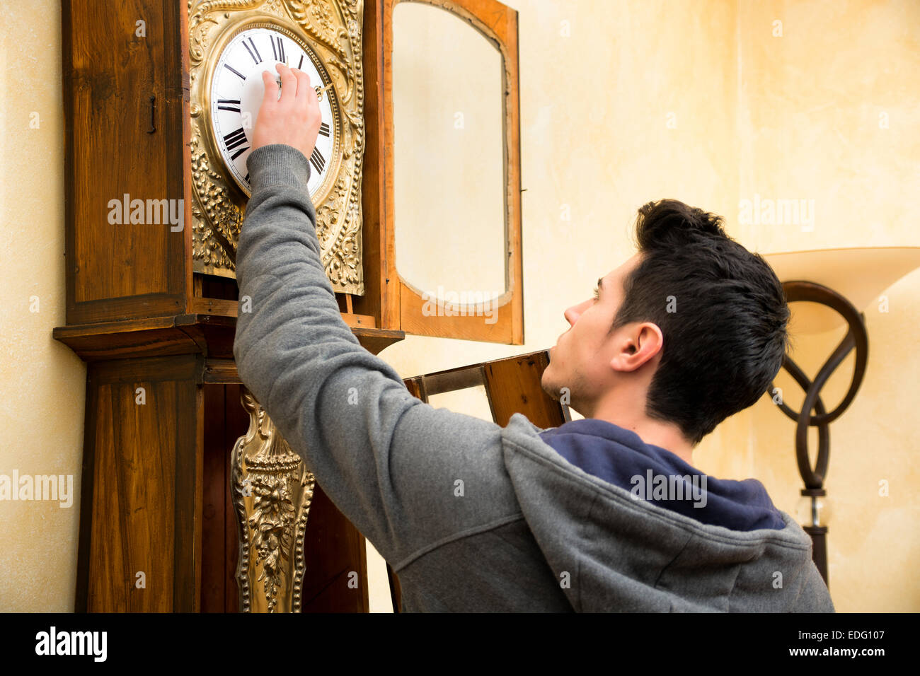Young man checking a pendulum and winding the mechanism Stock Photo