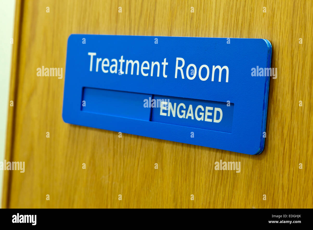 Treatment Room sign on a wooden door in a hospital with the Engaged part on display Stock Photo