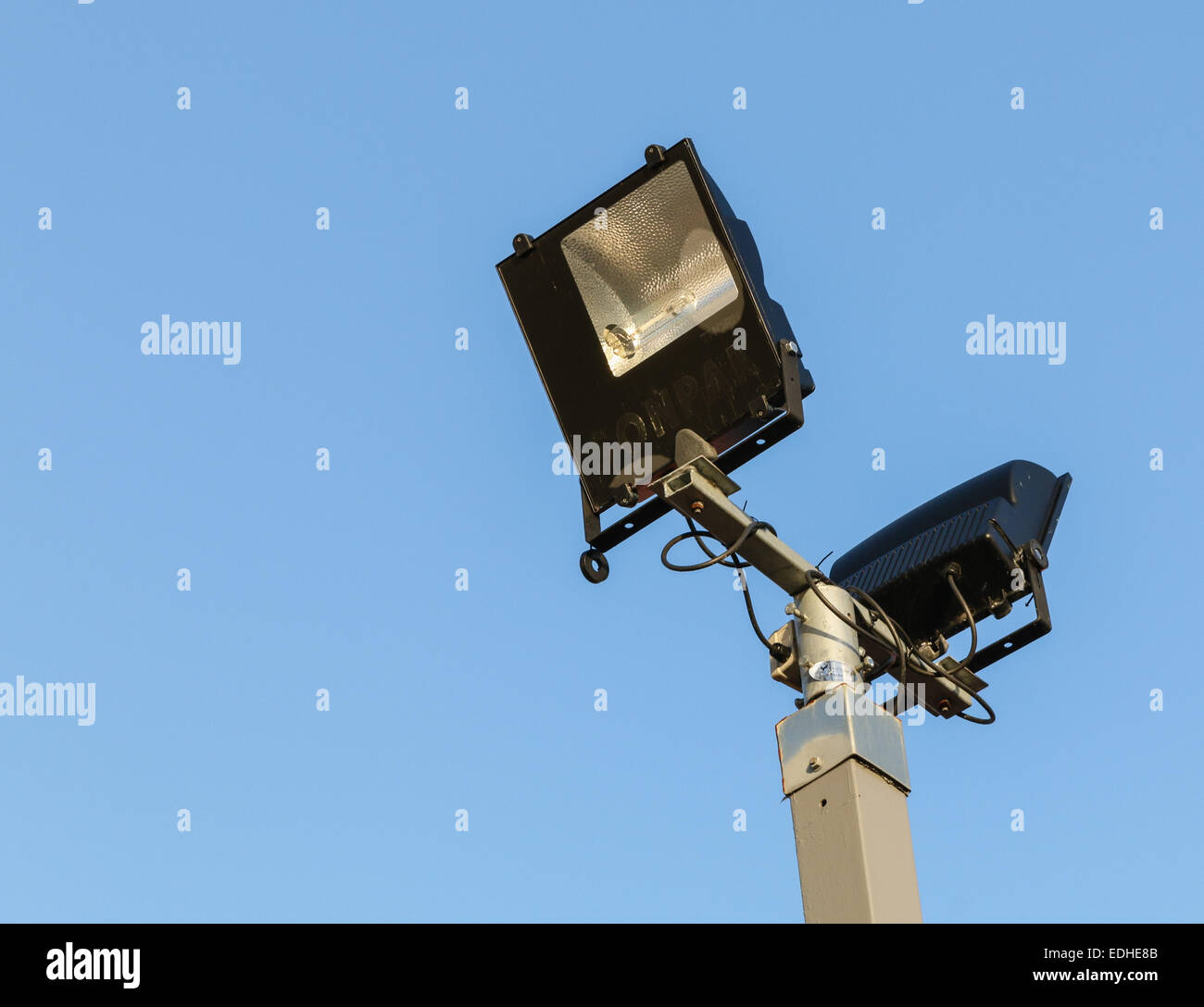 Security floodlights on a tall post against a winter blue sky at a UK shopping centre Stock Photo