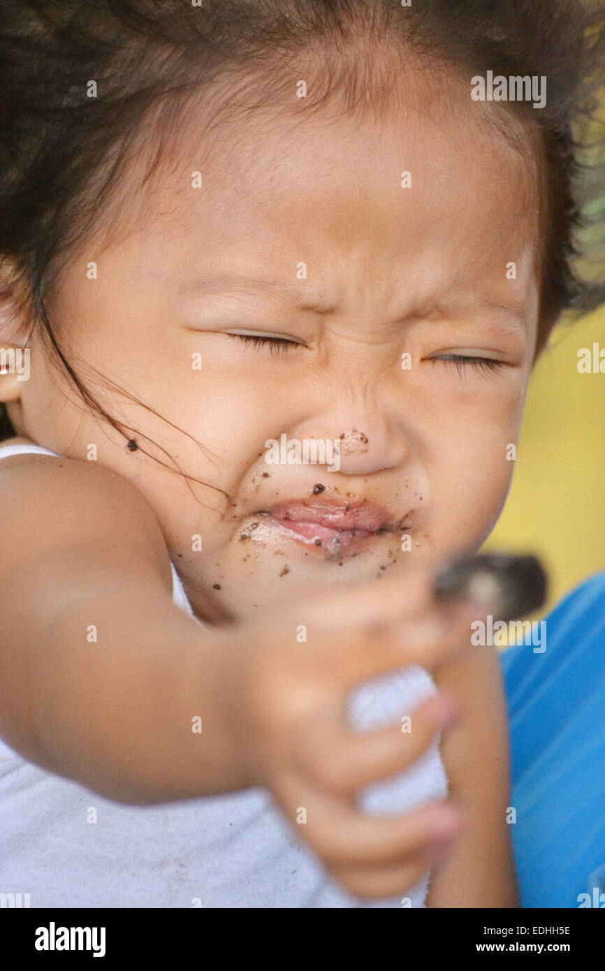 A portrait of beautiful asian little girl making a gesture in her face, doesn't want more chocolates Stock Photo