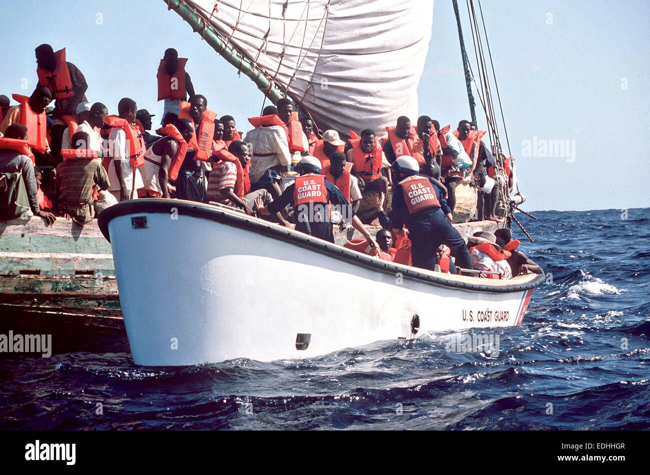 Haitian migrants scramble to get off a makeshift raft into a U.S. Coast Guard lifeboat after being interdicted at sea on their way to Florida November 10, 1991 in the Caribbean Sea. The refugees will be taken to camps in Guantanamo Bay, Cuba for repatriation. Stock Photo