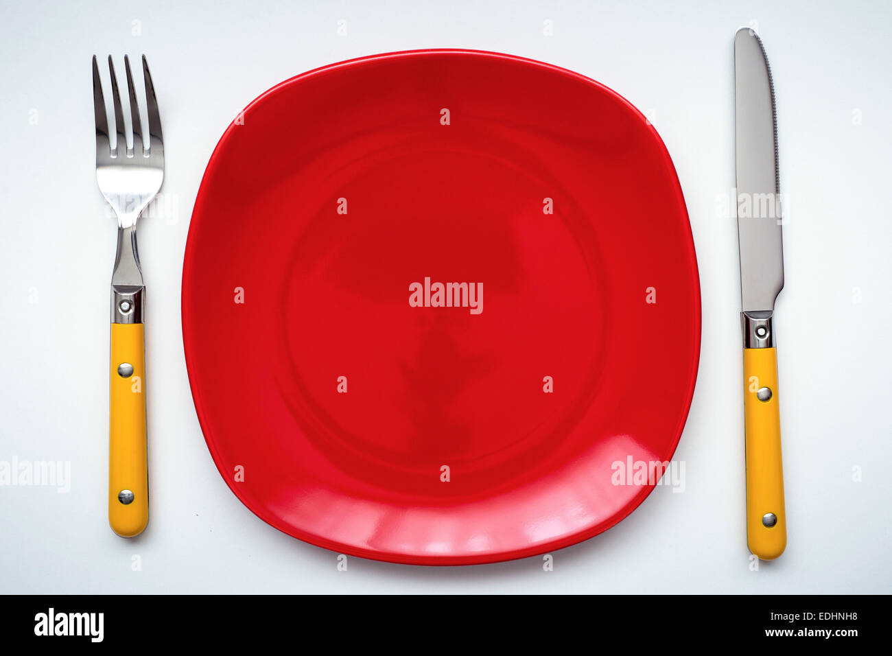 empty clean red with yellow cutlery on white background Stock Photo