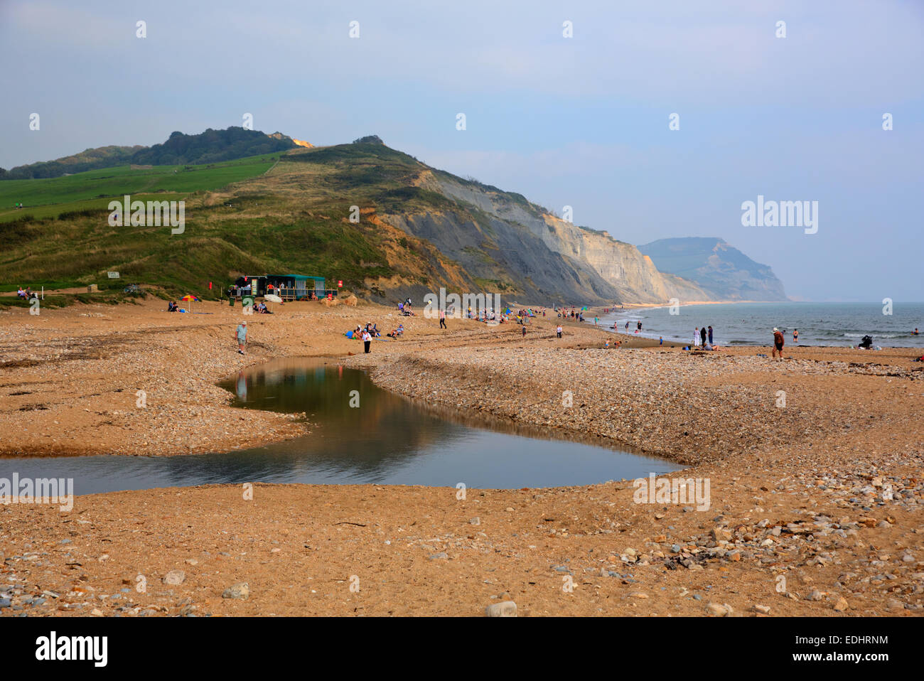 People on Charmouth beach and coast Dorset England UK with pebbles shingle green field and coastline Stock Photo