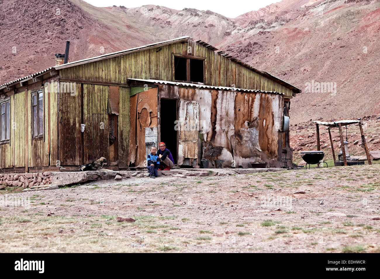 People sitting outside a delapidated hut, settlement on the Pamir Highway, M41, Province of Gorno-Badakhshan, Tajikistan Stock Photo