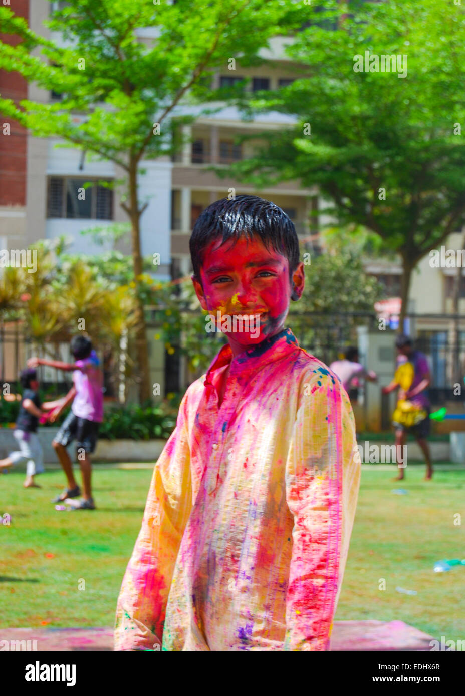 A young Indian boy playing with powder colors & water during the spring hindu festival Holi also known as a festival of colors. Stock Photo