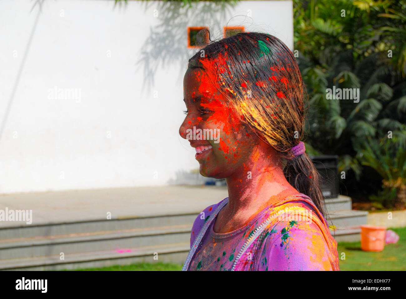 A young Indian girl covered in powder colors during the spring hindu festival Holi also known as a festival of colors. Stock Photo