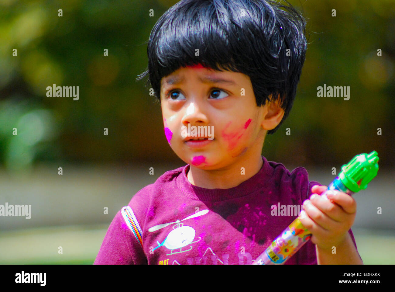 An Indian kid playing with powder colors & water during the spring hindu festival Holi also known as a festival of colors. Stock Photo