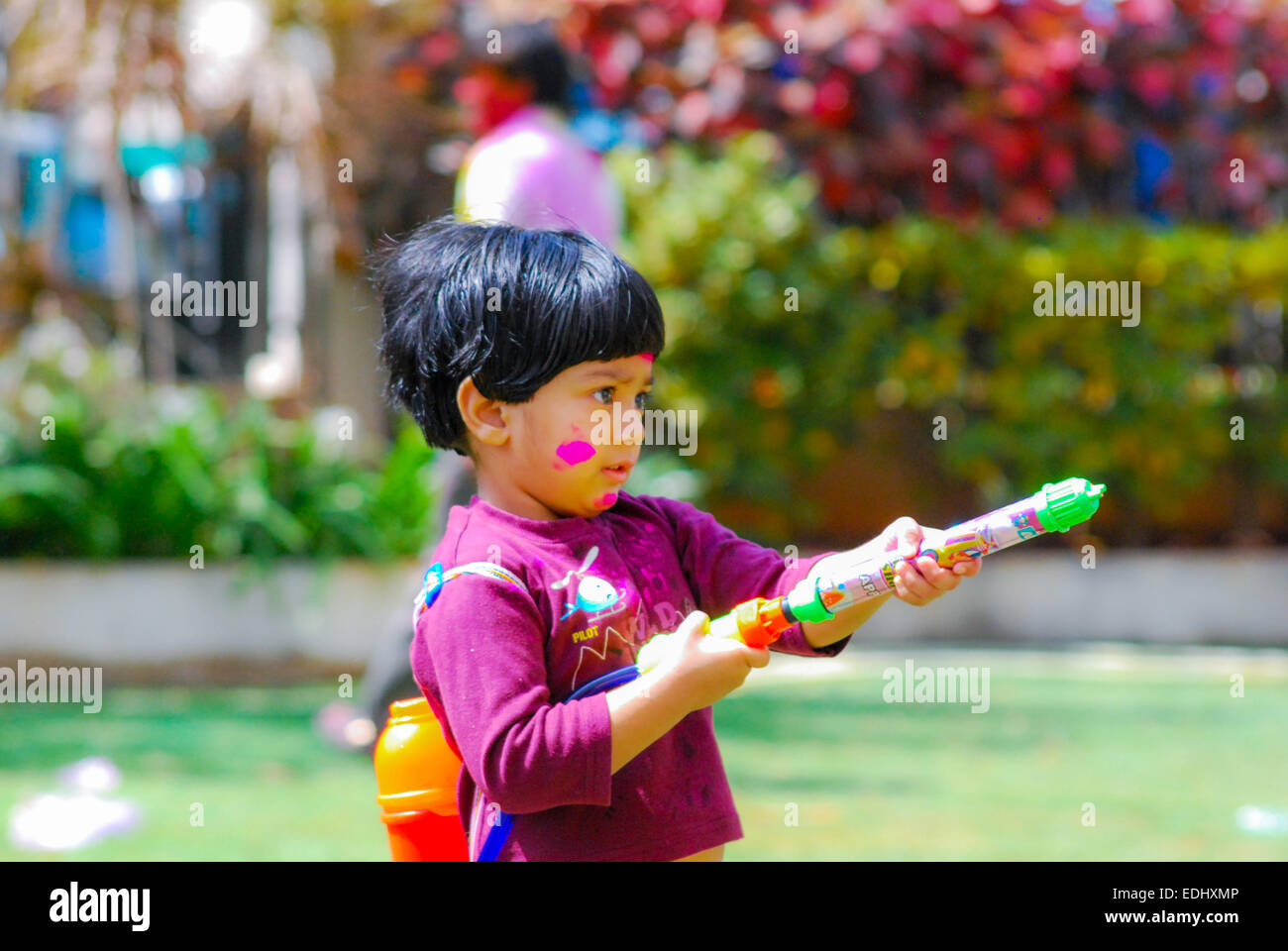 An Indian kid playing with powder colors & water during the spring hindu festival Holi also known as a festival of colors. Stock Photo