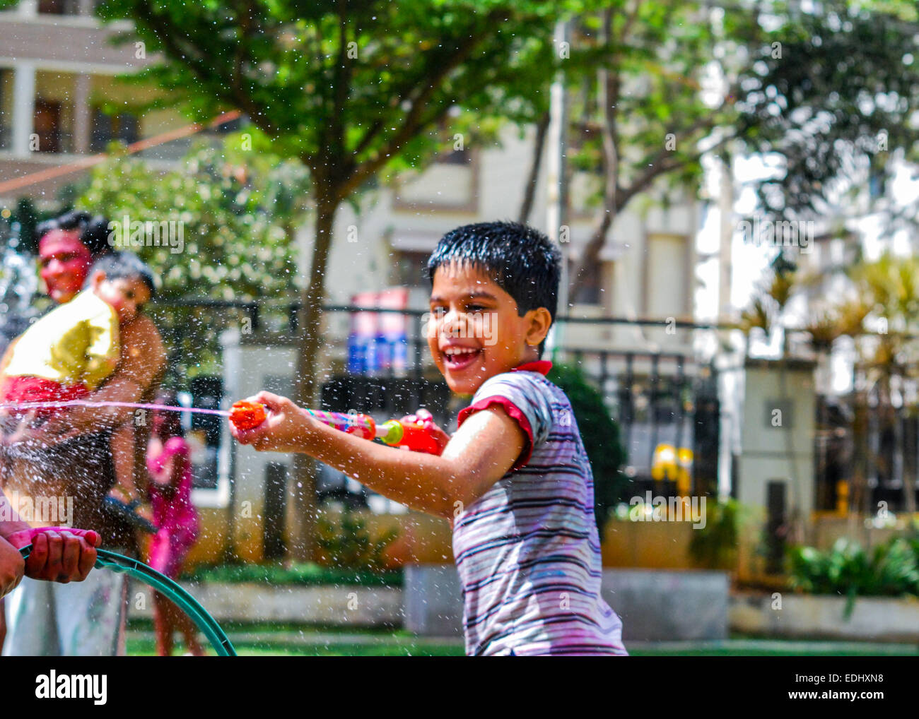 A young Indian boy playing with powder colors & water during the spring Hindu festival Holi also known as a festival of colors. Stock Photo