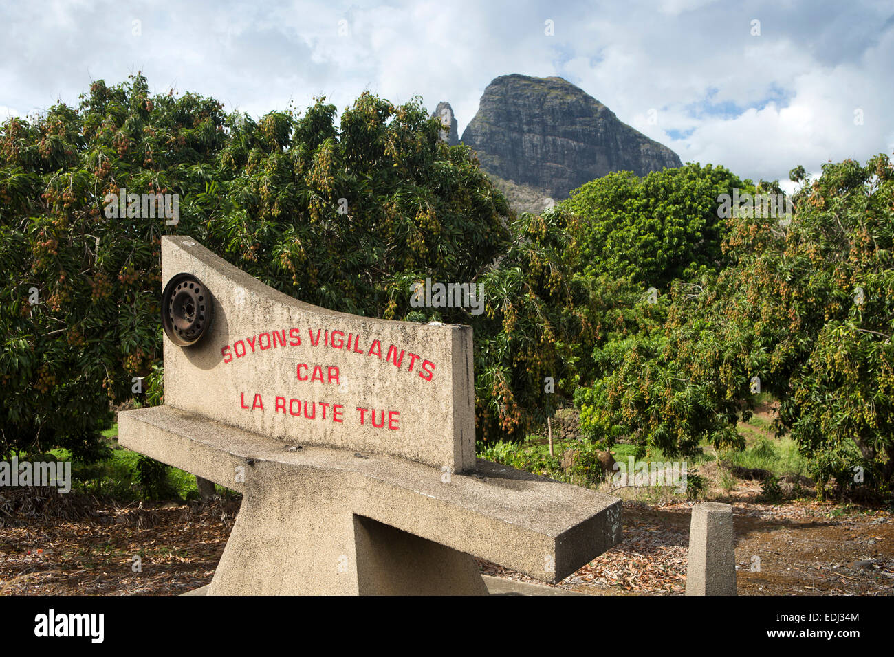 Mauritius, Quatre Bornes, montagne du Rempart and Trois Mamelles mountains beyond mango trees and safe driving sign Stock Photo