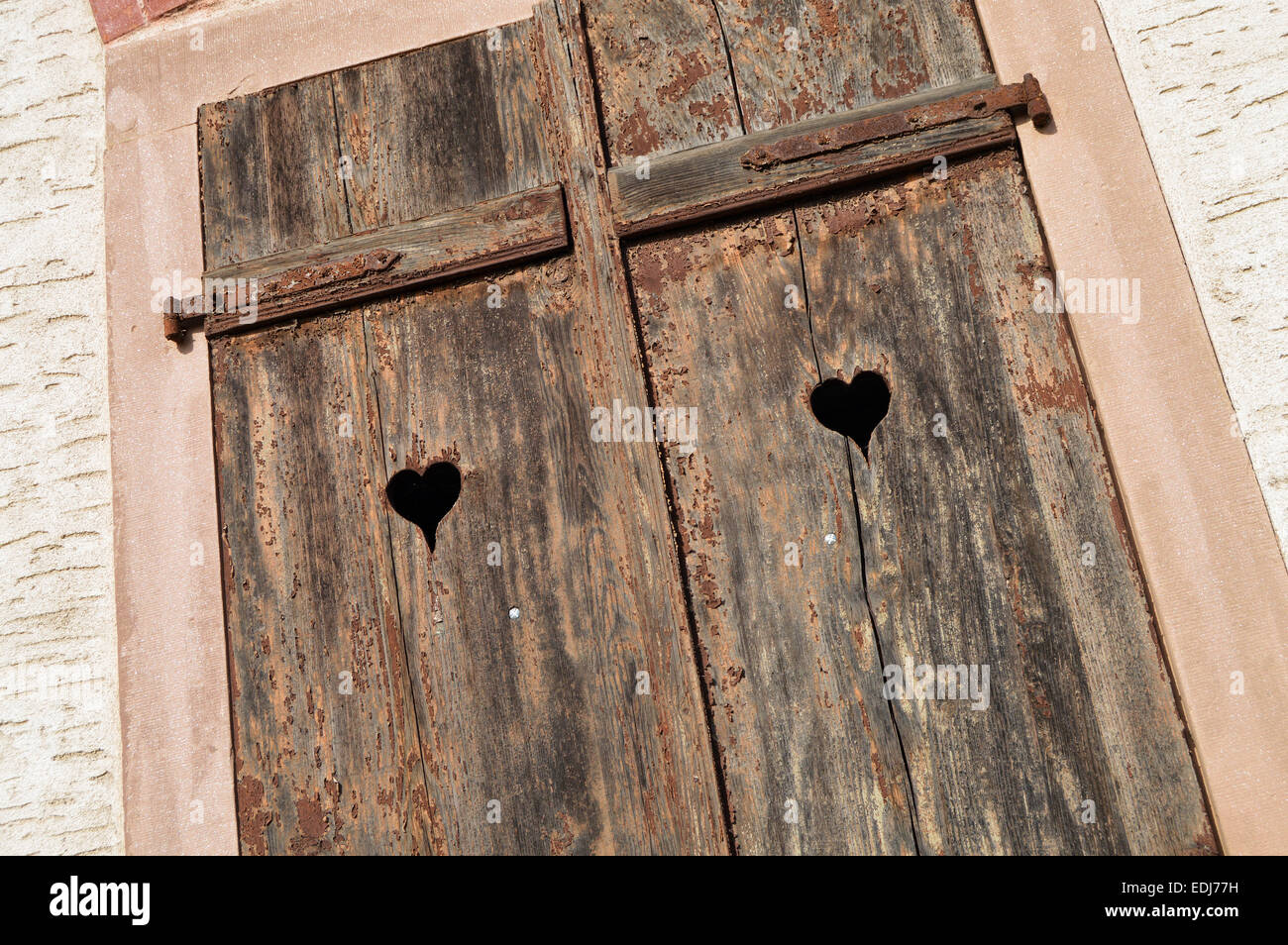 Closed old shuttered weathered wooden window with heart shape in the Alsace, France Stock Photo