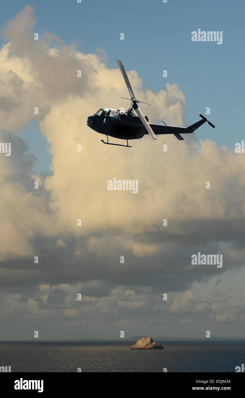 Helicopter approaching over water in early morning Stock Photo