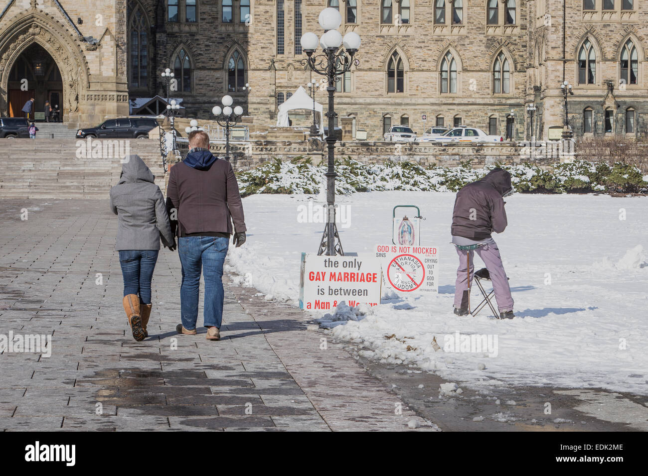 A couple walks by a lone same-sex marriage protester in front of the Parliament of Canada in Ottawa Stock Photo image
