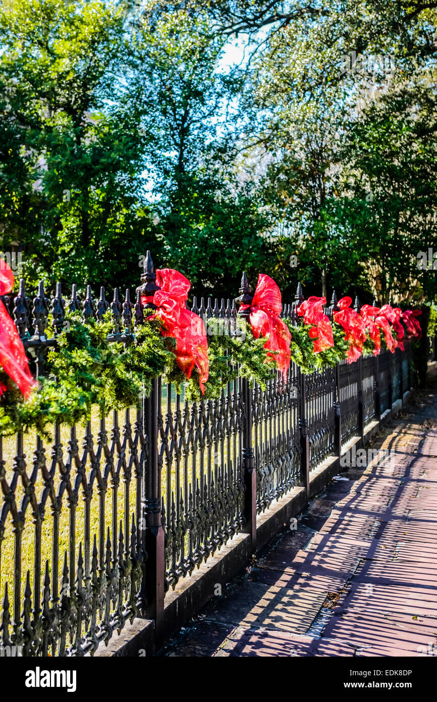 Red bows ties to a cast Iron ornate fence around a n estate in the Garden District of New Orleans LA Stock Photo