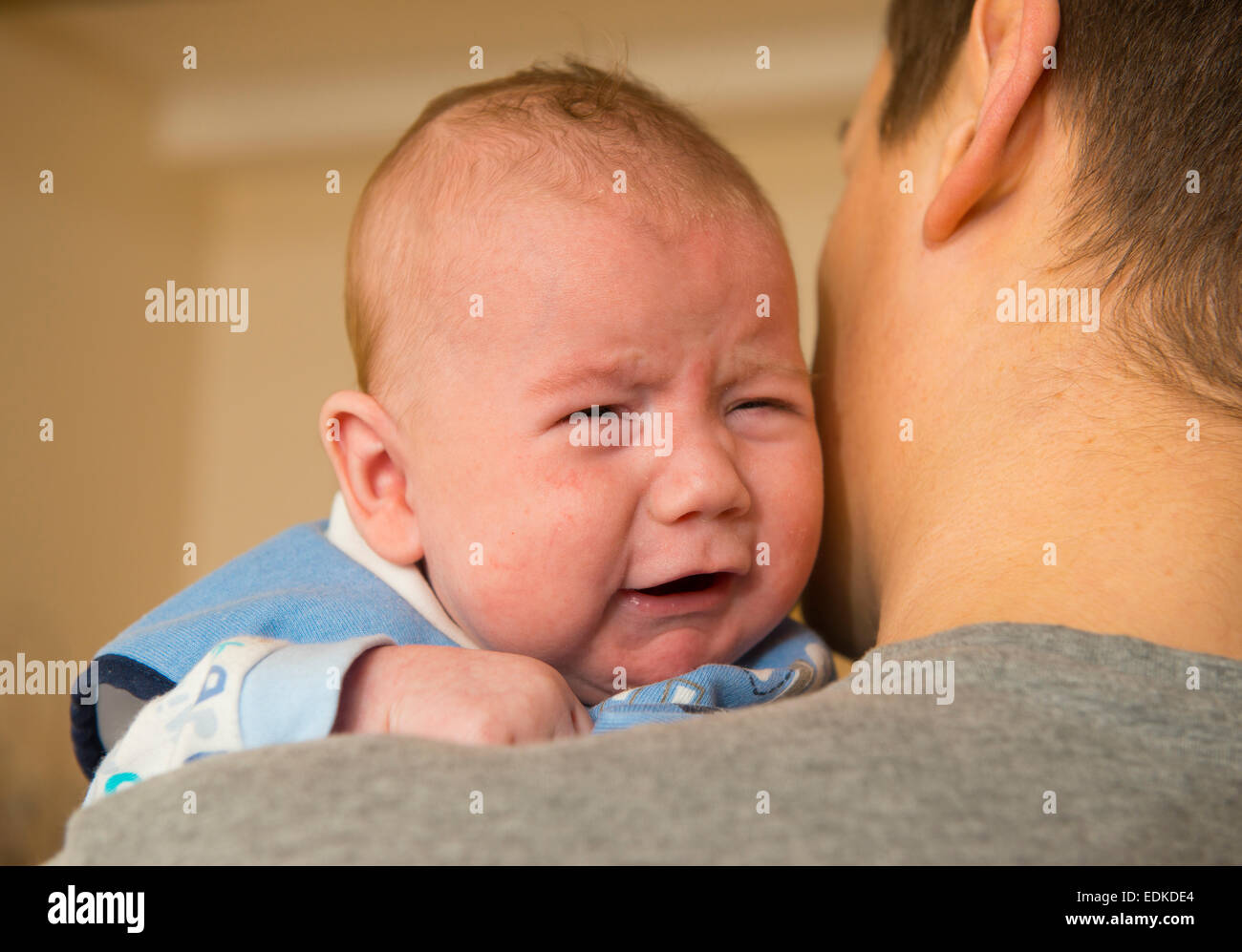 A two month old baby crying while being held. Stock Photo