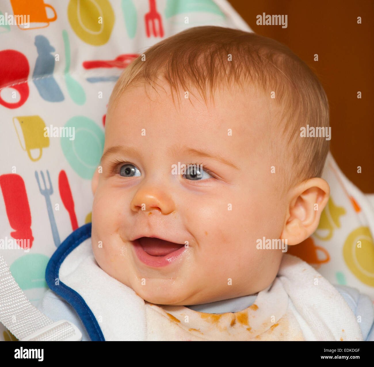 A seven month old baby smiling in a high chair Stock Photo Alamy