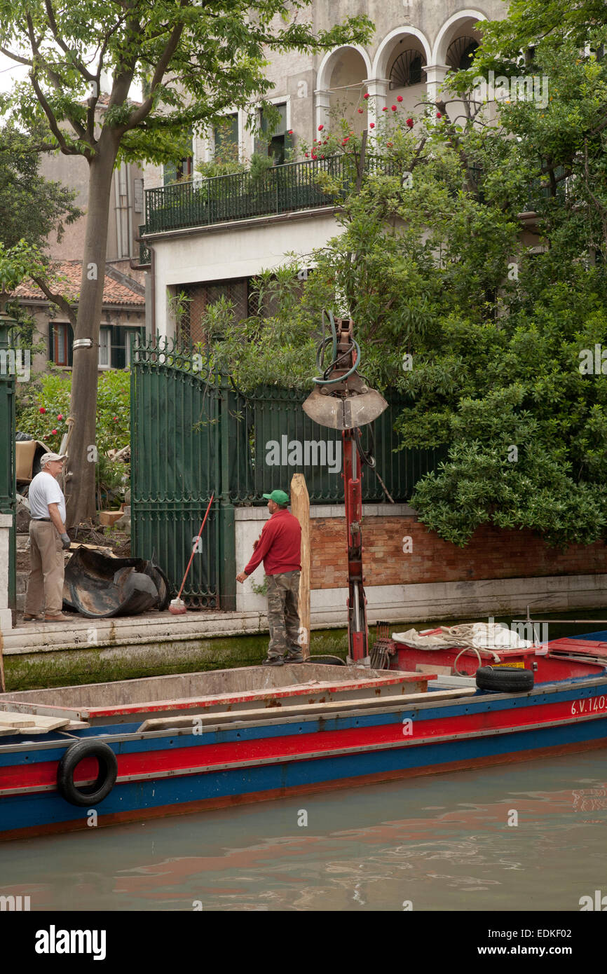Two workers conversing at a residence off a canal of Venice, Italy Stock Photo