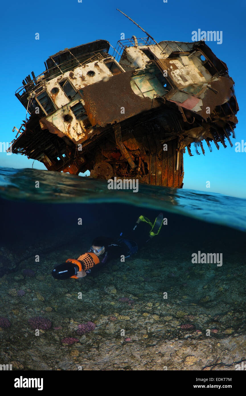 Split level, freediver swims to underwater scooter near the wreck, Red Sea, Egypt Stock Photo