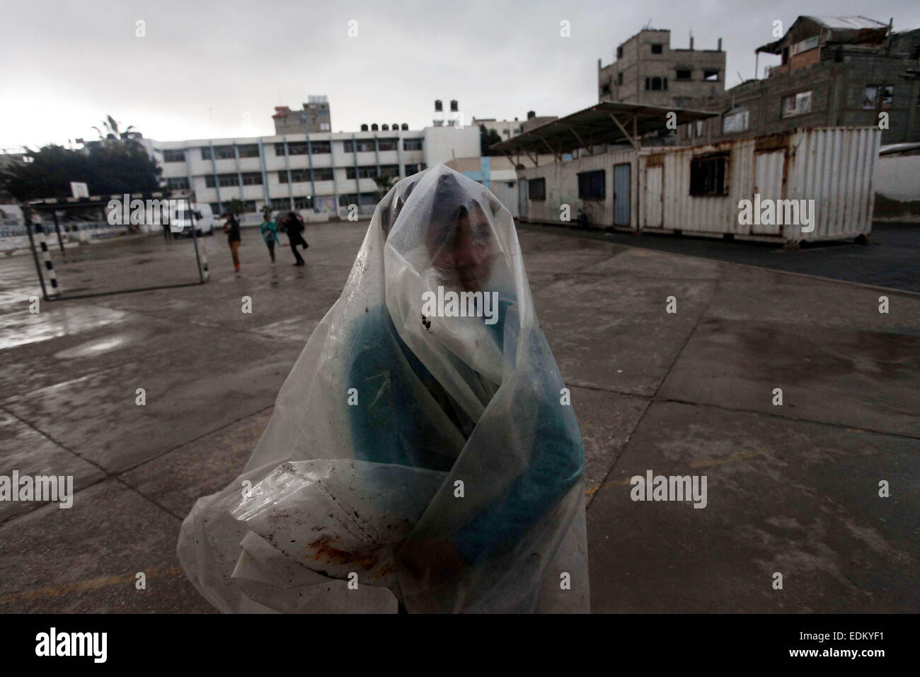 Gaza City, Gaza Strip, Palestinian Territory. 7th Jan, 2015. A Palestinian boy covers himself by a plastic sheet at a United Nations (UN) run school sheltering Palestinians, whose houses were destroyed in the most recent Israeli offensive on Gaza Strip, during a heavy winter storm in Gaza City on January 7, 2015. A storm buffeted the Middle East with blizzards, rain and strong winds on Wednesday, keeping people at home across much of the region and raising concerns for Syrian refugees facing freezing temperatures in flimsy shelters. The storm is forecast to last several days, threatening furt Stock Photo