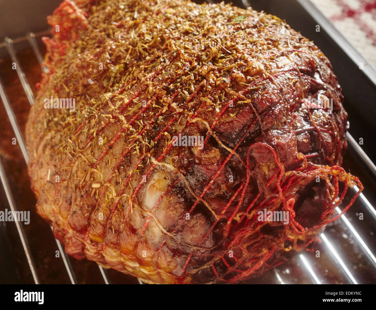 A roast leg of lamb with the bone removed. 'bone out leg of lamb.' The green spot in the upper right is a meat  thermometer Stock Photo