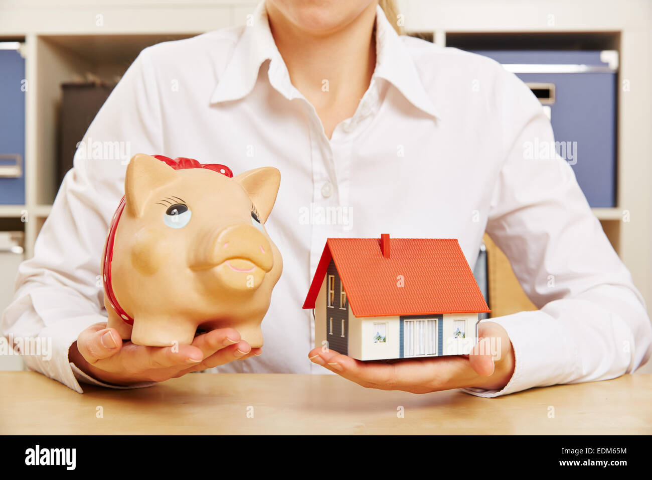 Building society savings concept with hands holding house and a piggy bank Stock Photo