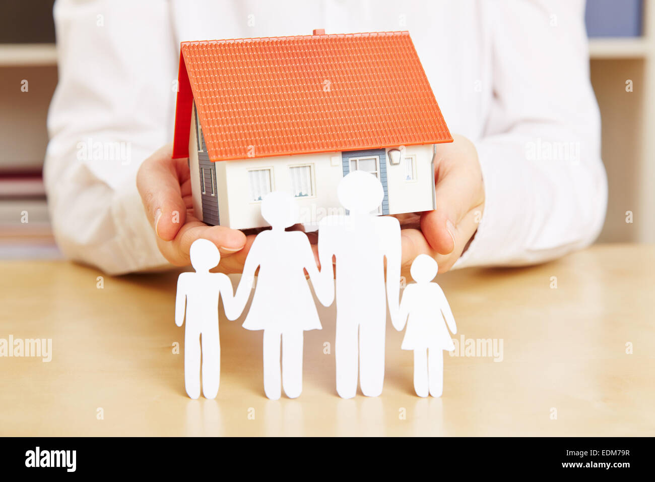 Paper family with kids and a house in the hands of a woman Stock Photo