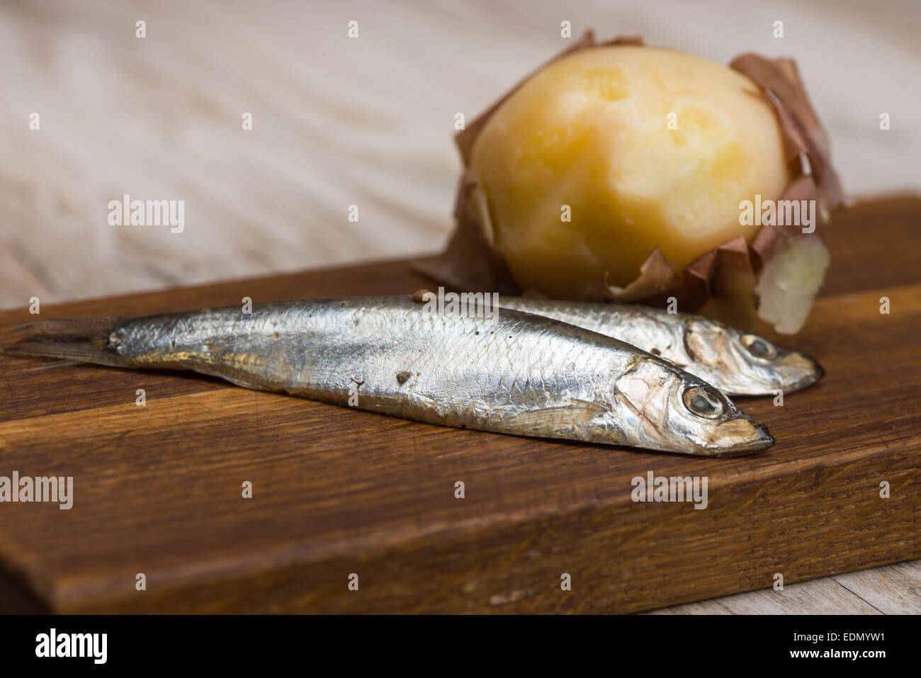 spicy salted anchovies and boiled potatoes on a wooden board Stock Photo