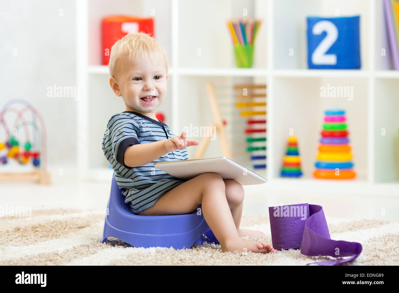 smiling child sitting on chamber pot indoor Stock Photo