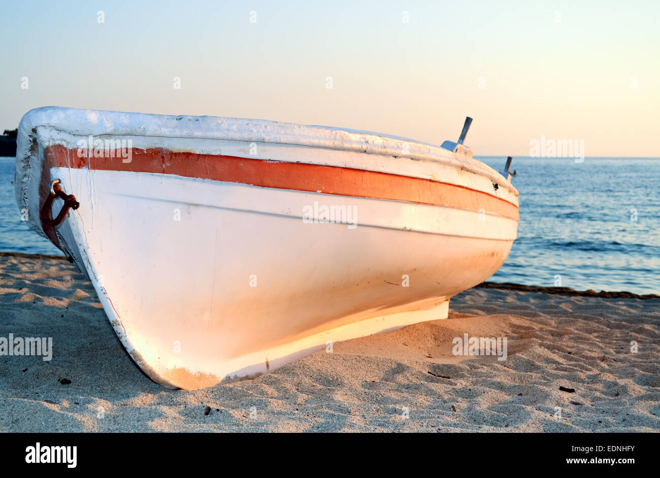 Small boat on the sandy shore at sunset Stock Photo