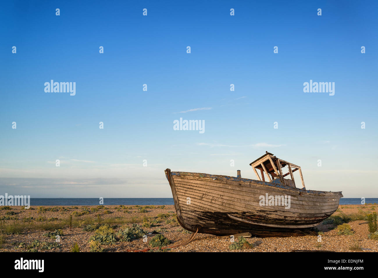 Abandoned fishing boat on shingle beach landscape at sunset Stock Photo ...